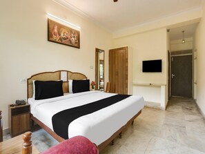 Een hotelkamer met een groot bed, een houten hoofdbord, een nachtkastje met een telefoon, een flatscreen televisie aan de muur en een houten kledingkast.