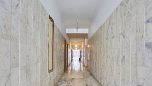 Un pasillo con paredes de mármol y suelo pulido, que conduce a una habitación con una puerta al final.