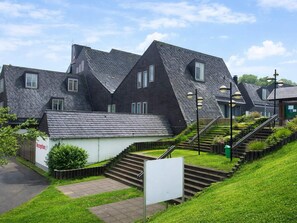 A modern building with a steeply pitched roof, a staircase leading to the entrance, and a small signboard. - 4 Person Holiday Park Home in Dienstweiler (Oberhambach)