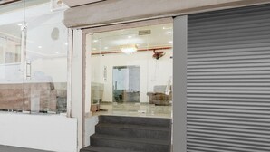 A modern interior with a staircase leading to a room, a closed roller shutter, and a visible door. - Saver Singlehotel Lotus (New Delhi)
