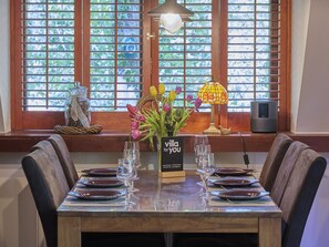 A dining table set with plates, glasses, and a vase of flowers.