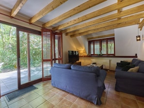 A living room with a sofa, a television, and a window with shutters.
