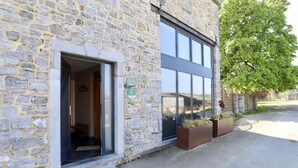 A stone building with a glass door entrance, outdoor planters, and a clear view of the street. - Charming cottage with a lovely terrace & garden (Gimnee)