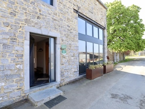 A stone building with a glass door entrance, outdoor planters, and a clear view of the street. - Charming cottage with a lovely terrace & garden (Gimnee)