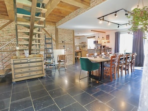 A spacious living area with a staircase, a dining table, and a kitchen in the background. - Charming cottage with a lovely terrace & garden (Gimnee)