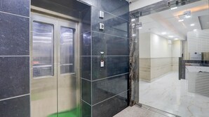 A modern elevator with a metallic finish, a glass door, and a control panel. - Premium Hotel O IIM Road Lucknow (Bakshi Ka Talab)