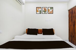 A bedroom with a bed, two black pillows, a wooden headboard, and three framed artworks on the wall. - Premium Hotel O IIM Road Lucknow (Bakshi Ka Talab)