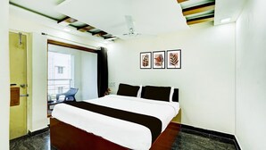 Een hotelkamer met een bed, een plafondventilator en lijstwerken aan de muur.