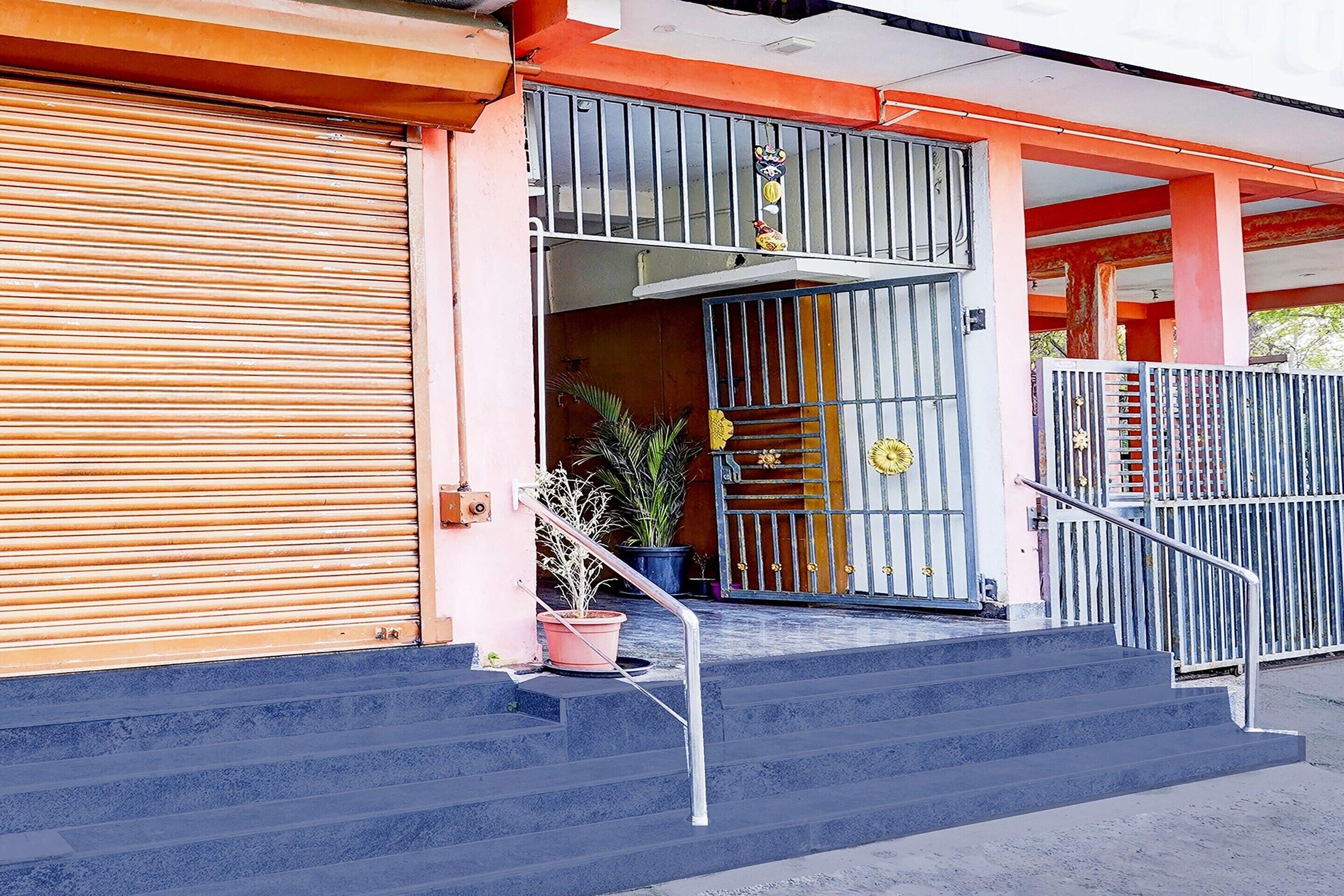A building entrance with a closed shutter, a metal gate, and a staircase leading to the entrance.