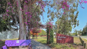 Un banco de parque, una pérgola y un cartel que indica Silvertop Park.