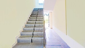 Una escalera con barandilla metálica que conduce a un espacio interior luminoso.