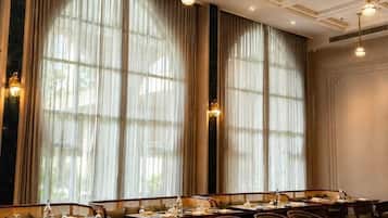 Un comedor elegante con mesas largas, sillas y candelabros.