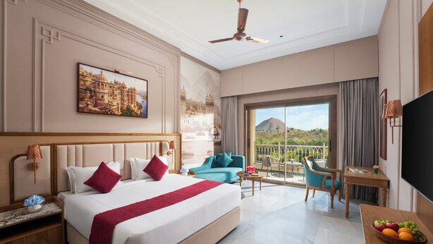 A hotel room with a large bed, a balcony with a view, a desk with a lamp, and a television. - Treat Imperial Hridhaan Udaipur (Udaipur)