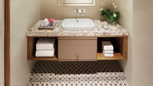 A bathroom with a marble sink, a mirror, a towel rack, and patterned floor tiles.