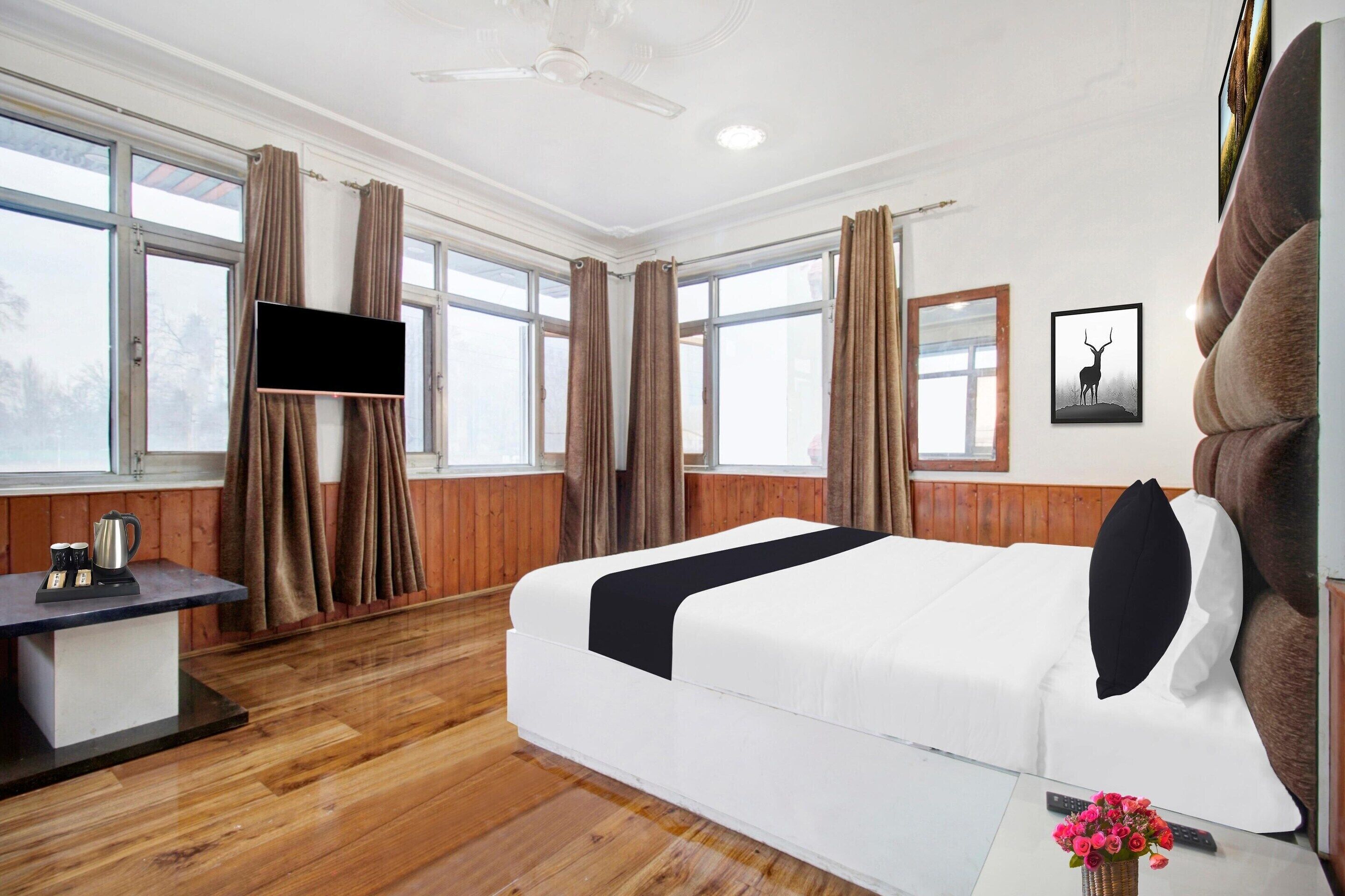 A hotel room with a bed, a desk, a TV, and a window with curtains.