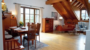 Ein geräumiger Loft mit Essbereich, einer Couch und einer hohen Holzbalkendecke.