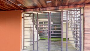 A metal gate with a window, a brick base, and a wooden ceiling. - Premium Hotel O IIM Road Lucknow (Bakshi Ka Talab)
