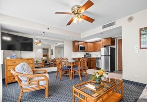 A modern living room with a dining area, a kitchen, and a ceiling fan. - Cozy 1-bedroom condo one short block from the beach! (Honolulu)