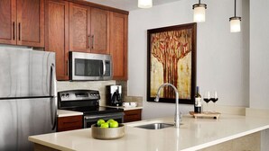 Una cocina moderna con electrodomésticos de acero inoxidable, gabinetes de madera, una isla grande con fregadero y una cafetera.