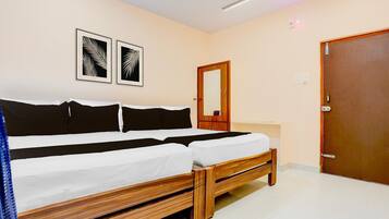 A double bed with a wooden frame, a bedside table, a mirror, and two framed leaf patterns on the wall.