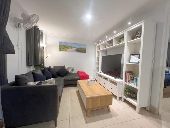 A living room with a sofa, a coffee table, a TV, and a bookshelf.
