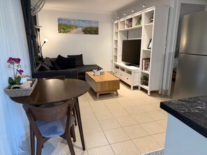 A modern living room with a sofa, coffee table, TV, and built-in shelves.