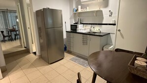 Cocina moderna con refrigerador, microondas y lavamanos. Hay un comedor con mesa y sillas.