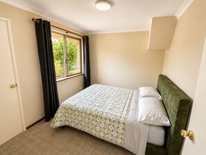 A bedroom with a bed, a window with curtains, a door, and a light fixture. - Perth Beach House (Mullaloo)