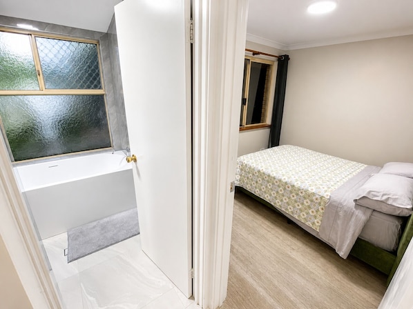 A bedroom with a bed, a window, and a door leading to a bathroom.