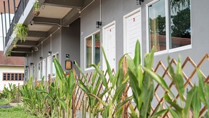 Una hilera de habitaciones de hotel con fachada gris, puertas blancas y ventanas numeradas.