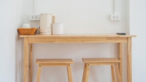 Una mesa de madera con una cafetera, una taza blanca y una cesta.