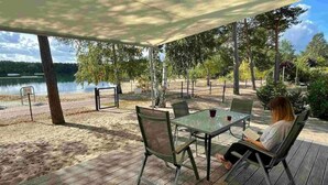 Um pátio externo com mesa e cadeiras, com vista para um lago.