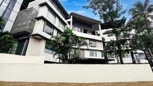 A modern multi-story building with a flat roof, large windows, and a balcony.