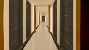 A long, narrow hotel corridor with dark doors on both sides and a shiny, reflective floor. - Collection O Lodha Experia Mall (Kalyan)