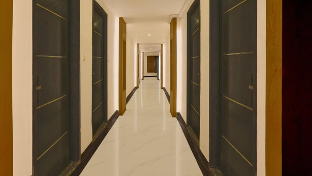 A long, narrow hotel corridor with dark doors on both sides and a shiny, reflective floor.