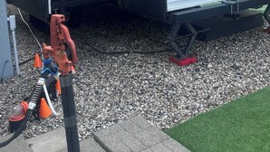 Jayco-merkkinen matkailuauto, jossa on liukuovi, ikkuna ja näkyvillä oleva vesiletku.