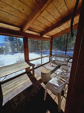 A wooden deck with a bench and chairs, overlooking a snowy landscape. - The Perfect Cozy Cabin of Elo Road! (McCall)