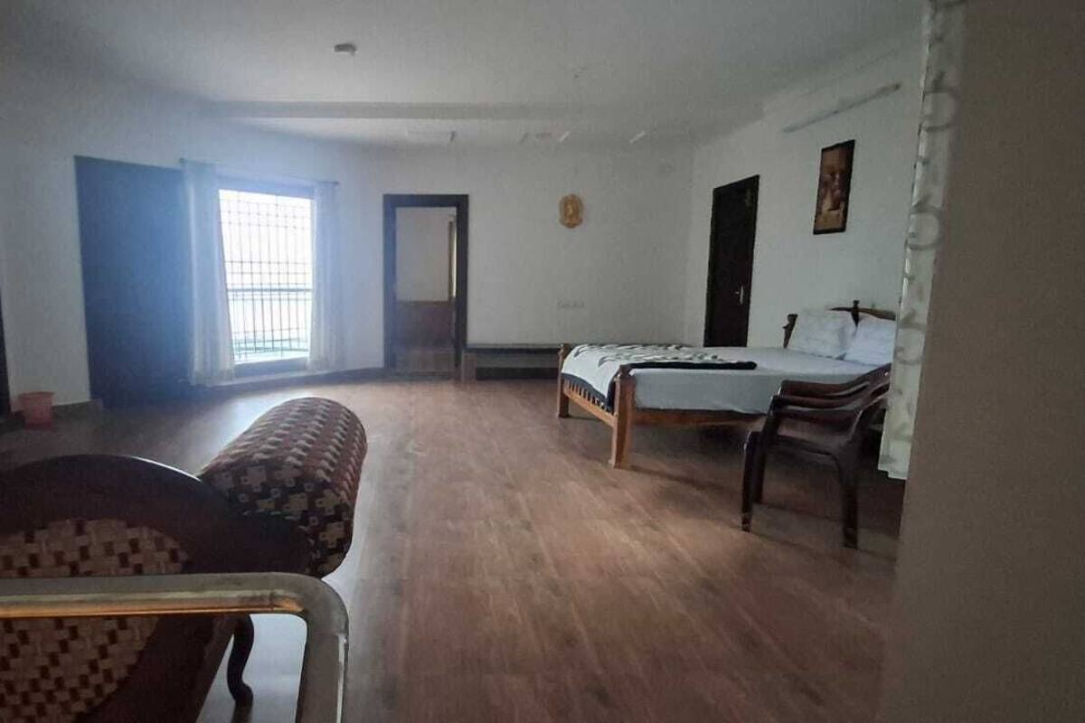 A room with a bed, a chair, a desk, and a window with curtains.