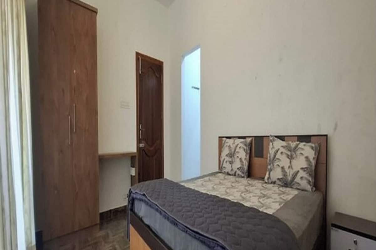 A bedroom with a bed, a wardrobe, and a nightstand.