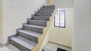 Eine Treppe mit Geländer, ein Fenster mit Gitterstäben und ein Lichtschalter an der Wand.