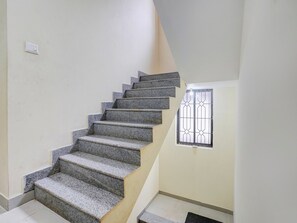 A staircase with a handrail, a window with metal bars, and a light switch on the wall.
