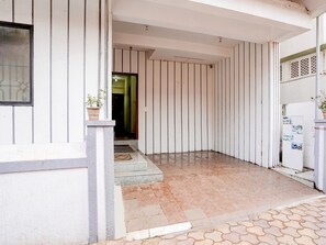 A corner of a building with a tiled floor, a door, and a window.