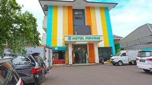Um edifício de vários andares com fachada colorida, uma placa com a inscrição 'HOTEL FIDUCIA' e uma entrada visível.