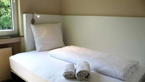 A neatly made bed with white linens and rolled towels, a bedside lamp, and a window with a view of greenery. - 2 Person Holiday Park Home in Bendorf (Bendorf)