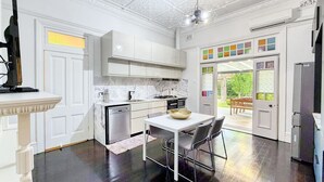 Una cocina moderna con armarios blancos, una mesa de comedor con sillas y vistas al exterior a través de un ventanal.