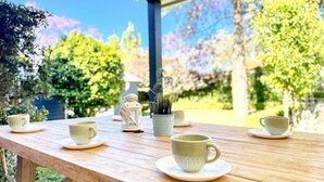 Una mesa de madera con tazas y platillos de té, un calentador de tetera y una pequeña figurita.