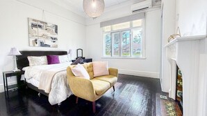 Un dormitorio con cama, sofá, candelabro, chimenea y un ventanal grande.
