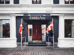 The entrance to Hotel Jomeroane with a red carpet, two flags, and a black awning. - 1 Person Holiday Park Home in Aalborg (Aalborg)