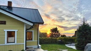 A yellow house with a dark roof, a wooden deck, and a stone wall. - Klaukse in Kolga-Aabla: Only 40 min. from Tallinn, sandy beach in 10 min. on foot. (Kolga-Aabla)