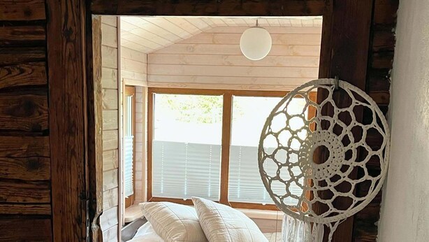 A cozy cabin room with a bed, a dreamcatcher, and a view through a window. - Klaukse in Kolga-Aabla: Only 40 min. from Tallinn, sandy beach in 10 min. on foot. (Kolga-Aabla)